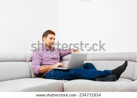 Handsome man browsing the web and sitting on a couch