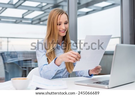 Happy businesswoman reading business report