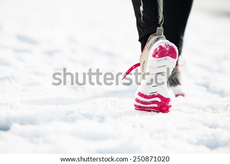 Closeup of female runner shoe running on snow