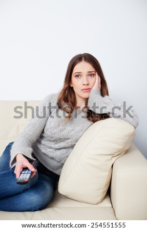 Sad woman watching television and changing channels