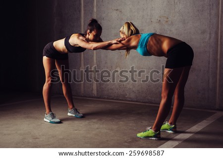 Two women stretching before gym workout