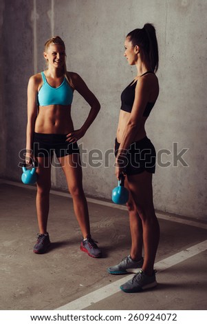 Two women standing with kettlebell in empty garage