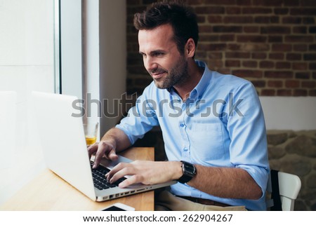 Happy man working on laptop at restaurant