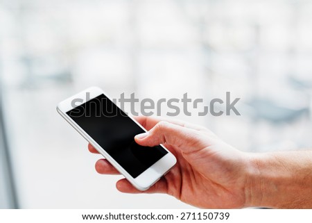 Hand of a man holding a smartphone and touching the screen