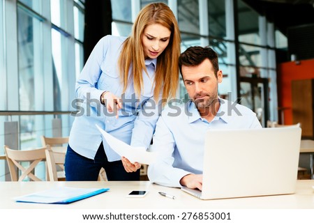 Two dissatisfied sales managers comparing data in an office