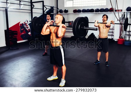 Group of men training with barbells. Clean and jerk competition at gym.