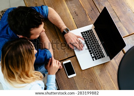 young couple with laptop at cafe against wooden table - mockup