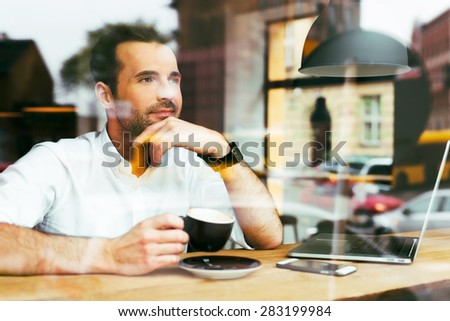 thoughtful man looking through window at cafeteria.