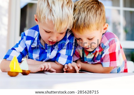 Photo of twin brothers playing together on digital tablet