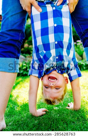 Young boy upside down at park, playing with mother