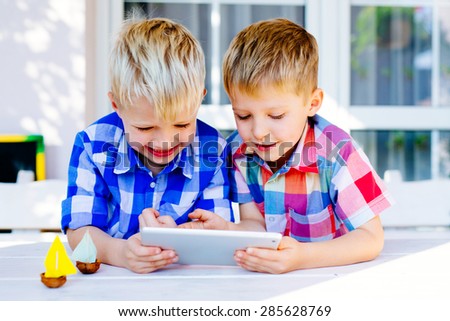 Two brothers having fun playing on digital tablet outside the home