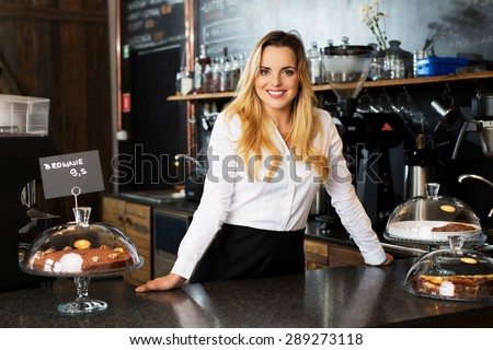 cheerful waitress standing behind the bar at cafe