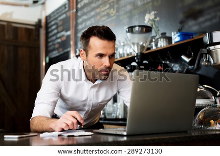 Restaurant manager working on laptop, counting profit
