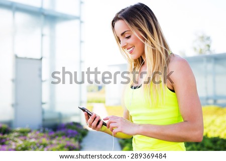 Young happy runner checking her smartphone