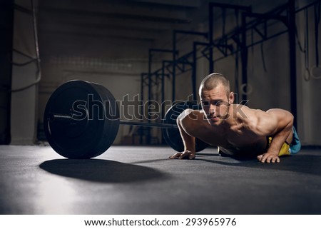 Burpees over the bar - young man training at gym