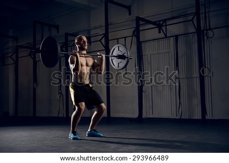 Clean and jerk exercise - young man training at gym