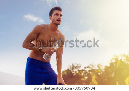 Tired athlete resting with bottle of water