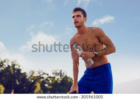 Runner resting with bottle of water in hand after intense workout