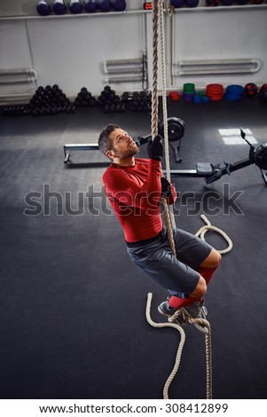 Athlete during rope climb exercise at gym