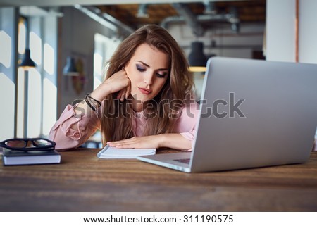 Unhappy female student tired of doing homework sitting at cafe with laptop