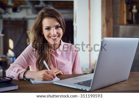Happy female student learning with laptop at cafe