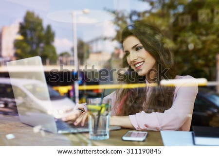 Young happy student at cafe typing on laptop