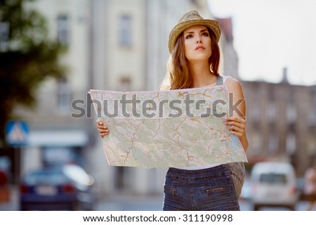 Female tourist with map visiting city and looking around