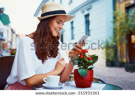 Happy woman with smartphone in outdoor cafe