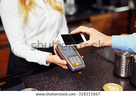 Paying with smartphone. Closeup of man making payment transaction with his mobile phone