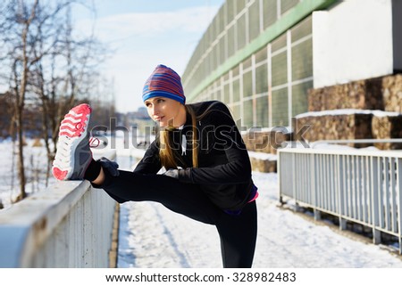 Female runner stretching before running at winter
