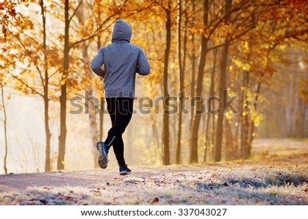 Young man running in the park during autumn morning