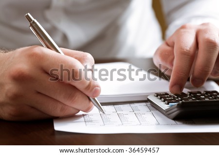 Financial data analyzing. Counting business data with calculator on the table closeup