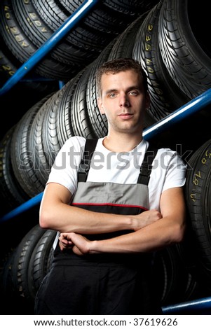 Young mechanic standing next to tire shelves