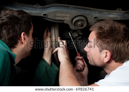 Two auto mechanics repair car in auto service