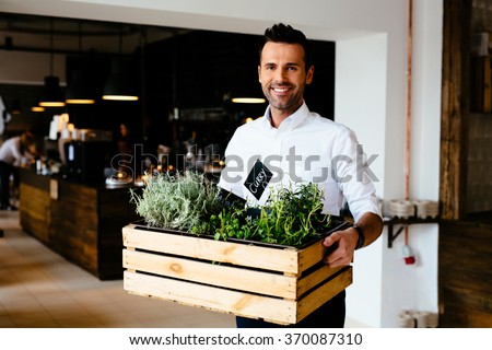 Happy restaurant manager holding box with fresh spices