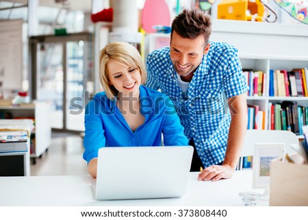Happy student and teacher learning in library on laptop computer
