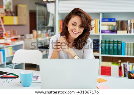 Happy small business manager working on laptop in bookstore