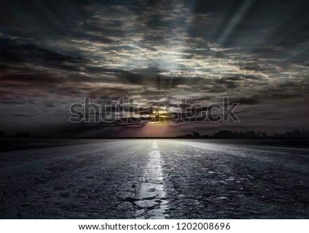 Magnificent view of the asphalt road in the background of the sunset. The road between the fields of wheat and steppe grass. Beautiful sunset on the horizon