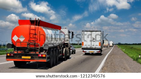 A highway with trucks, tank trucks. Against the background of the blue, cloudy sky