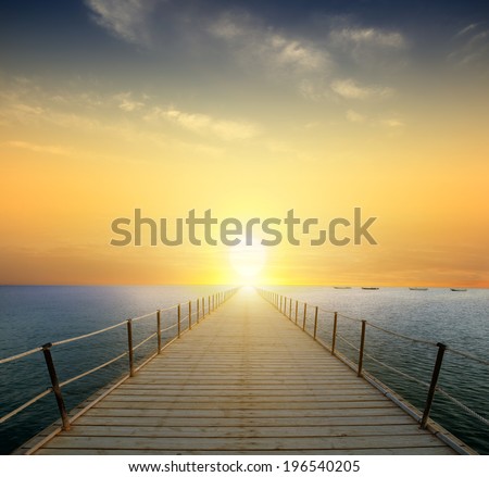ocean sunrise with pier and beach in foreground