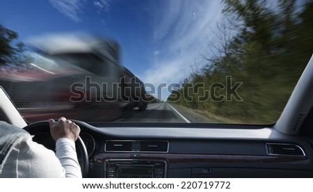 Driver in car holding steering wheel. Blurred road and sky