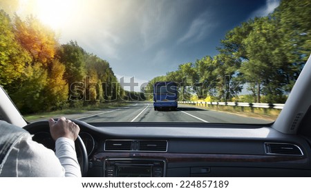 Hands on steering wheel of a car driving on an asphalt road