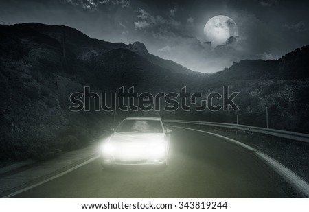 Driving on an asphalt road towards the headlights of car at night