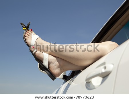 . Woman legs out the windows in car above the clouds.