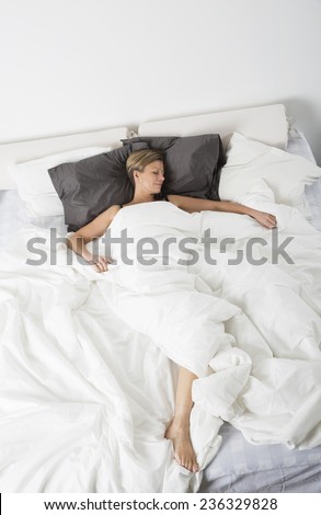 Woman sleeping in a white bedroom environment from high angle view