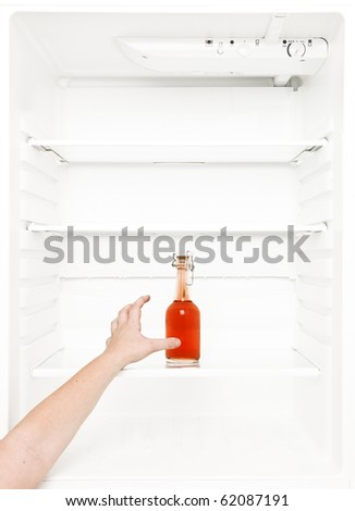 Human hand trying to reach a bottle in the fridge