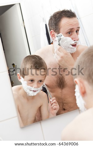 Happy Mature Man shaving in bathroom with his son