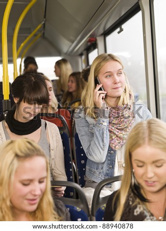 Young woman on the phone while going by the bus