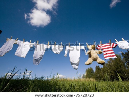 Baby Clothing and a teddybear on a clothesline towards blue sky