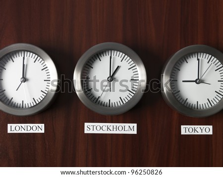 Three clocks with different time on Teak background